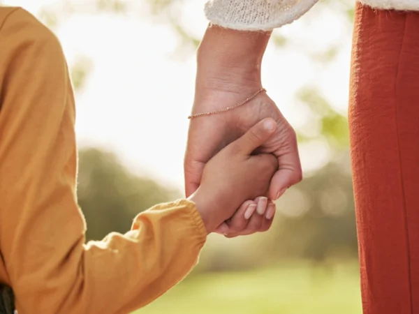 Close up of parent and child holding hands in a grassy outdoor area